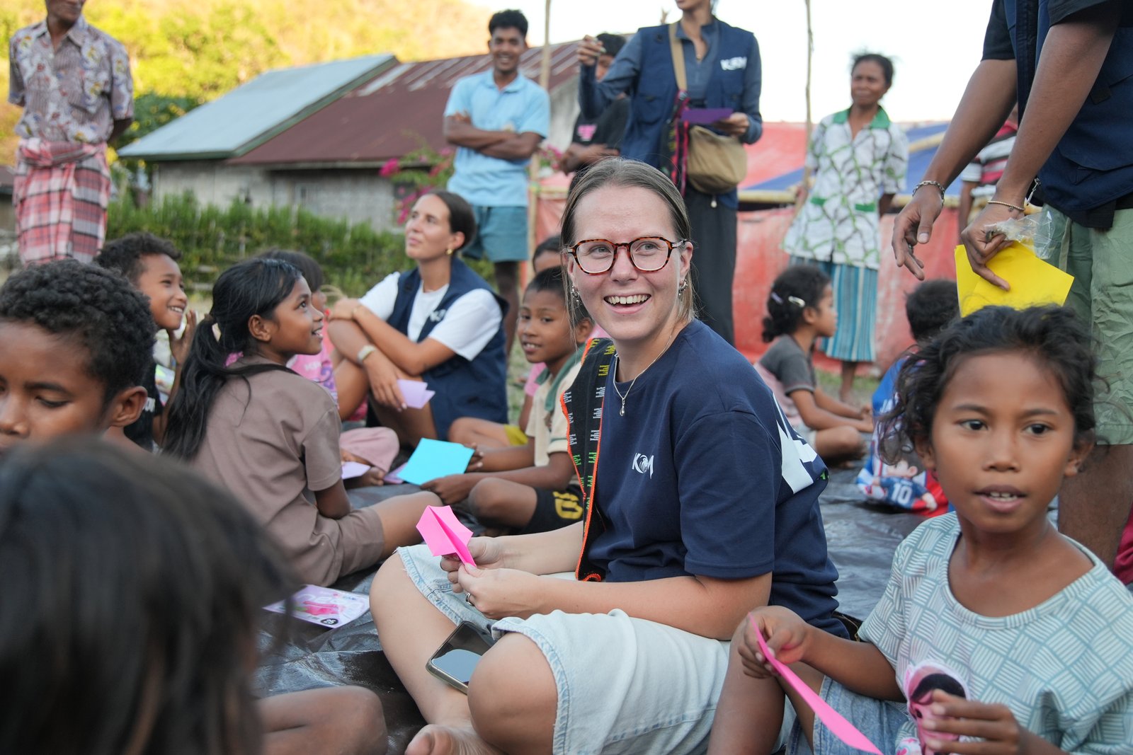 A KGM ambassador sitting with children in the community